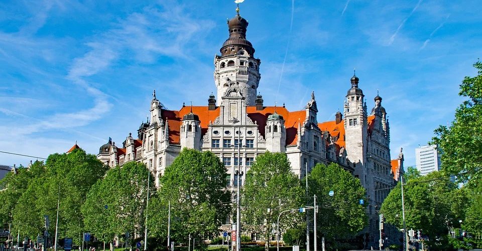 Das neue Rathaus Leipzigs, umgeben von grünen Bäumen bei blauem Himmel