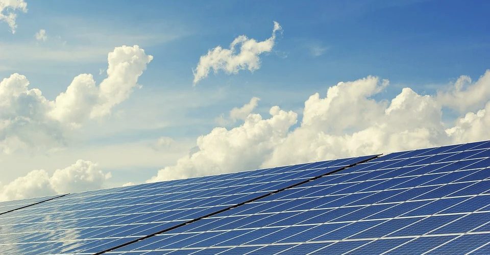 Große Solarthermieanlage, im Hintergrund blauer Himmel mit Wolken und Sonenstrahlen